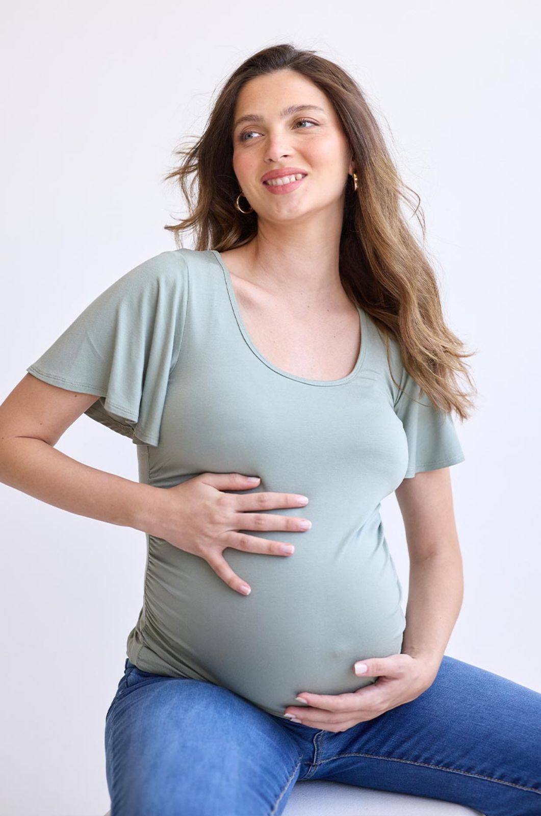אישה לובשת 	חולצת הריון בילי זית בהיר